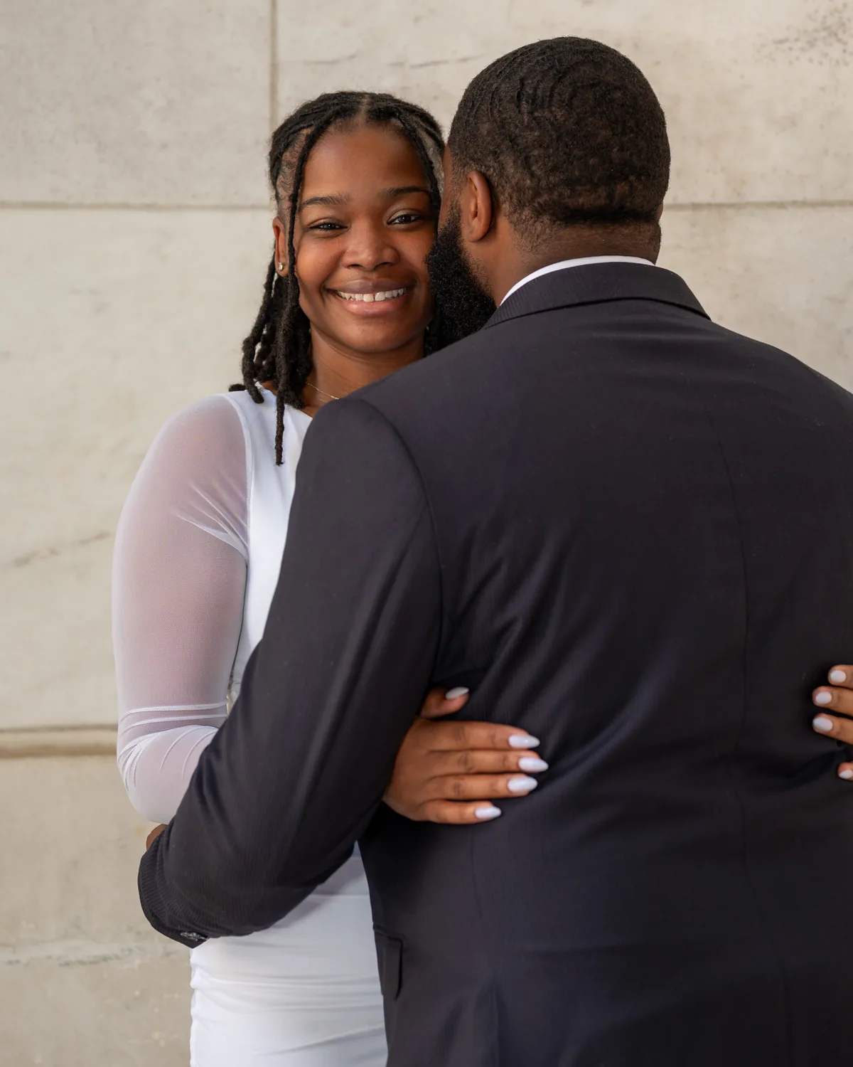 Woman smiling as her partner leans close against a stone wall