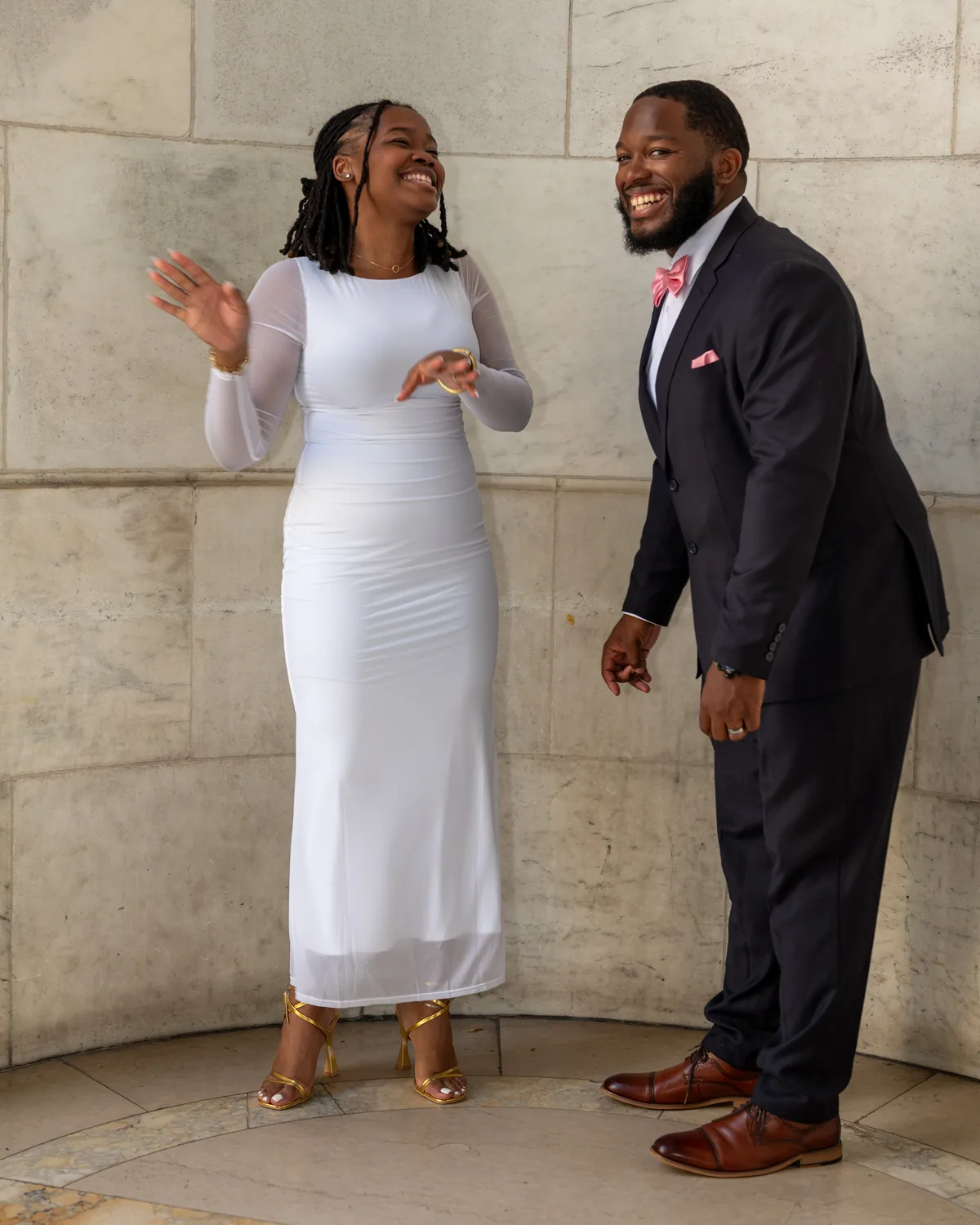 Couple laughing together beside a stone wall