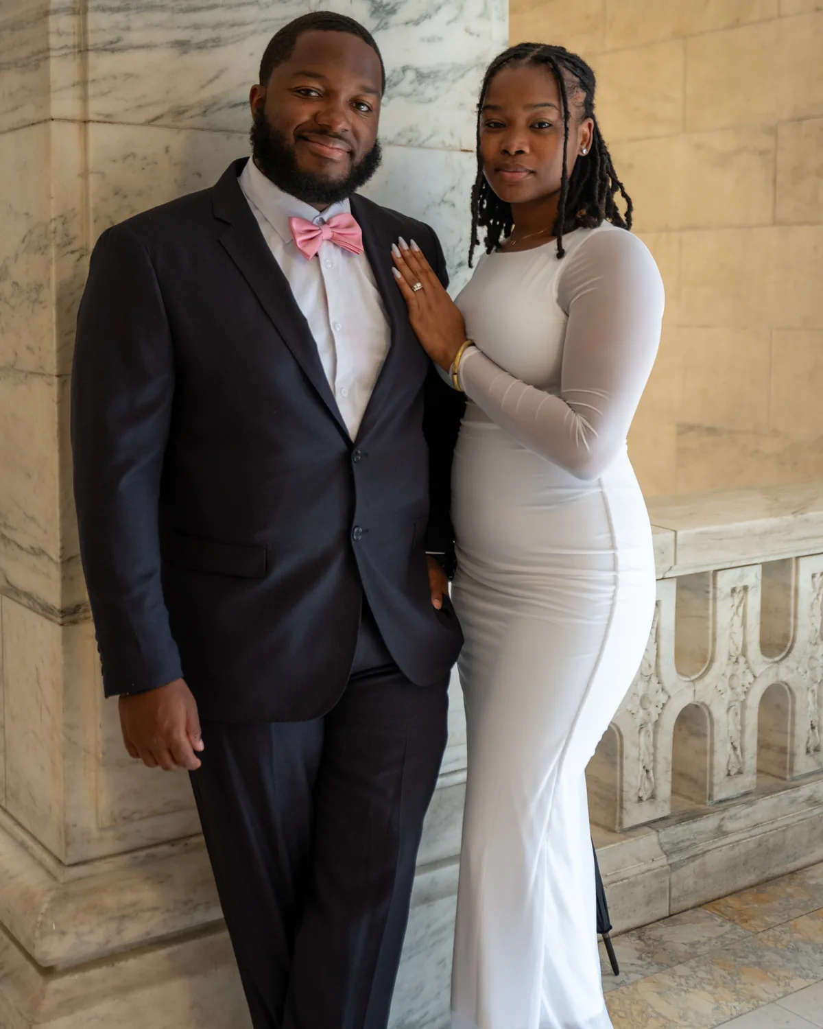 Couple standing close in formal outfits inside a stone hall