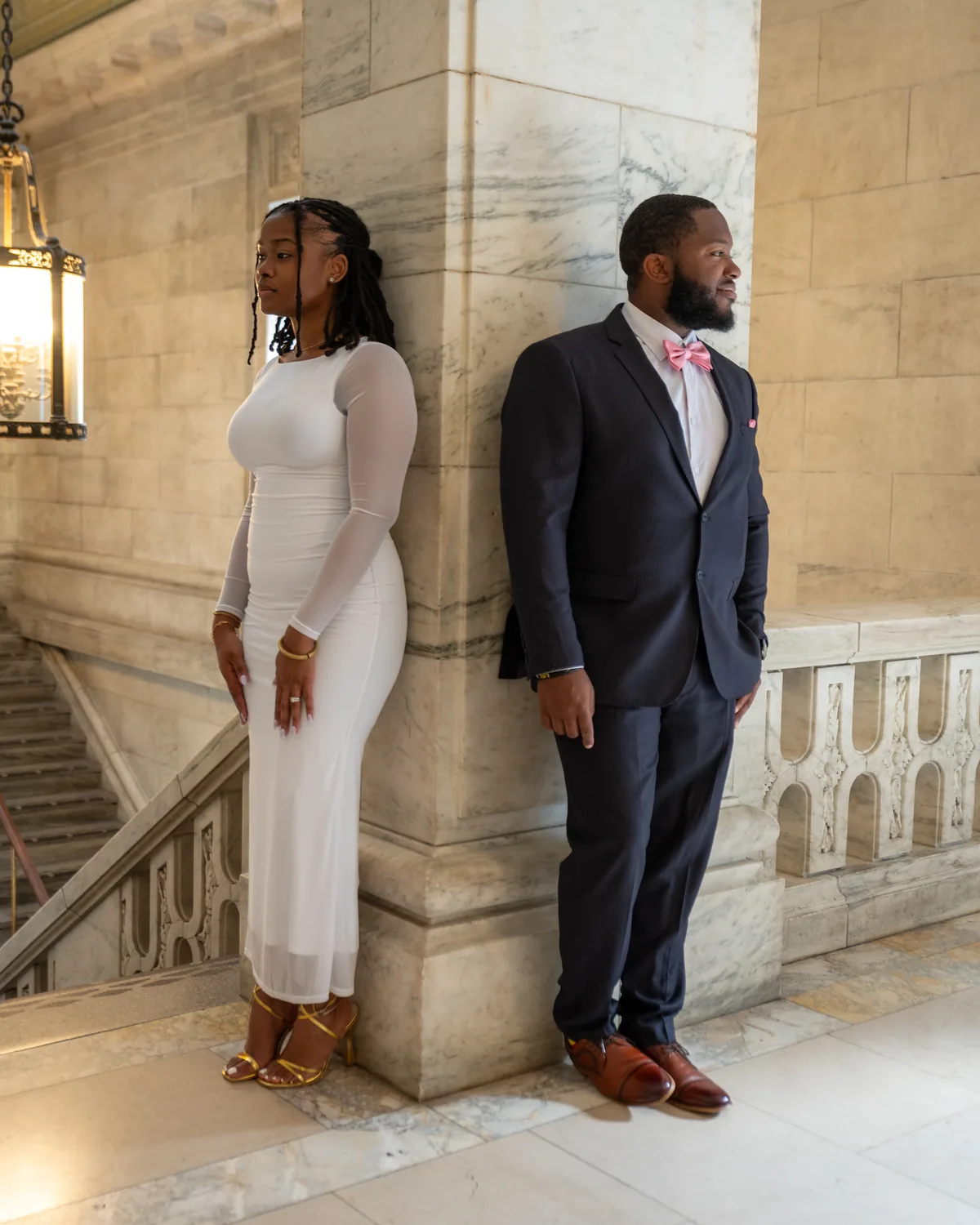 Couple looking in opposite directions beside a stone staircase