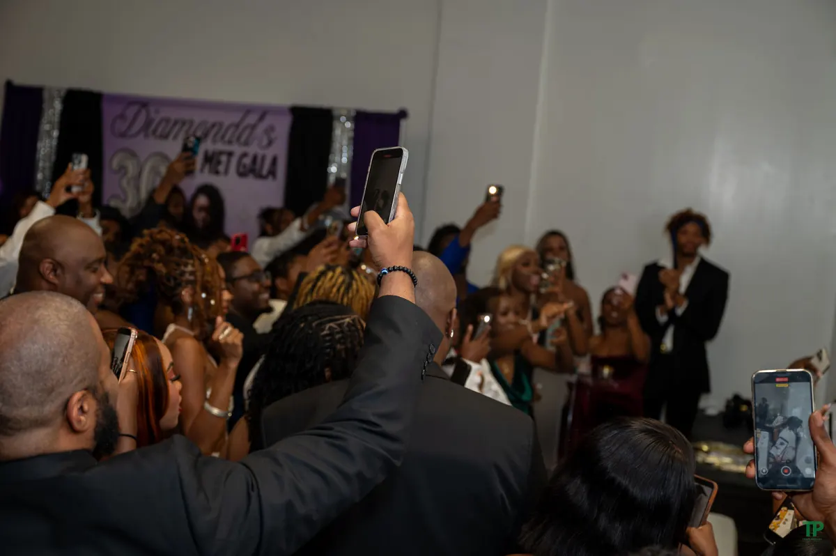 Party guests cheering and recording a celebratory moment during a birthday gathering