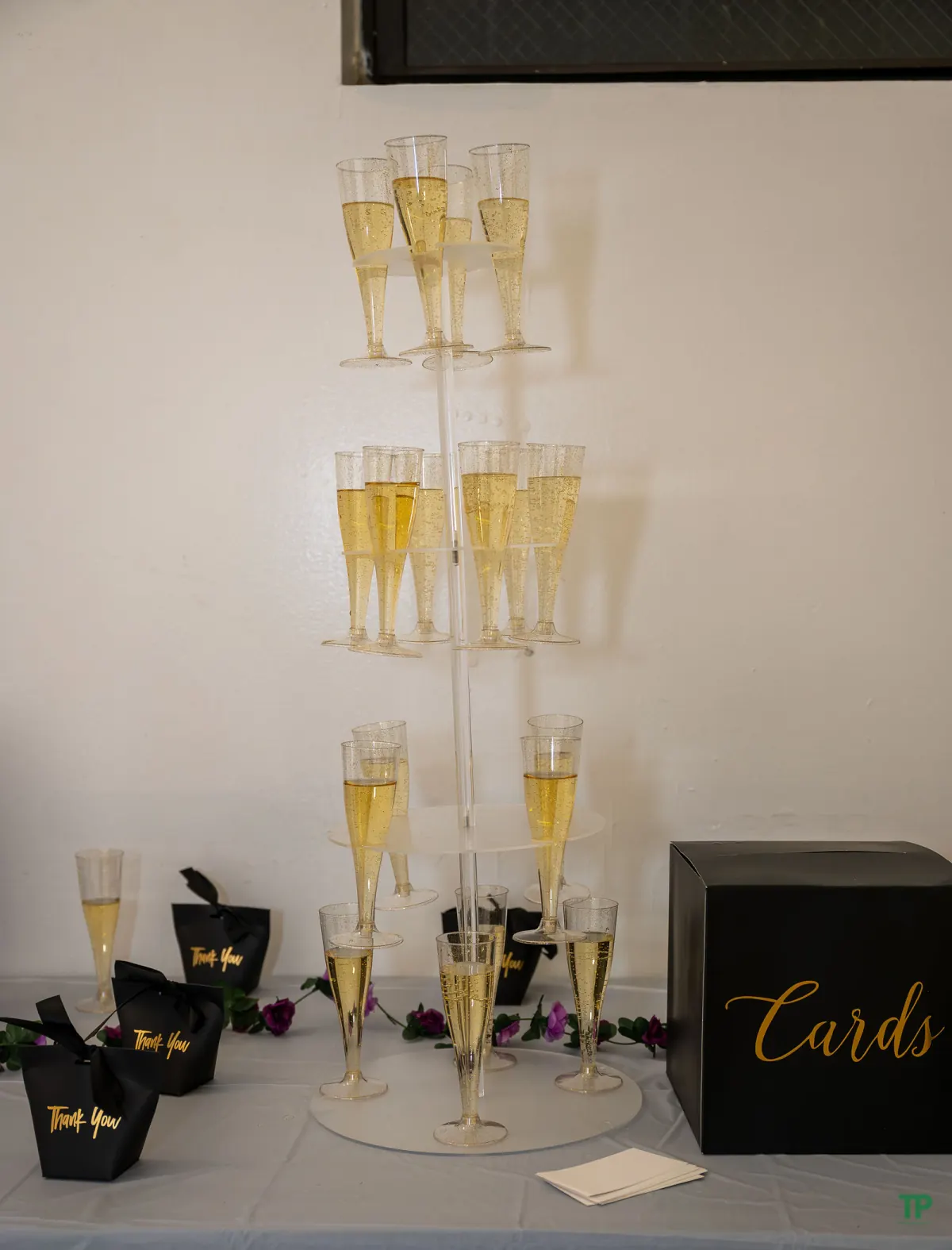 Champagne tower and party favors at a purple-and-gold birthday celebration