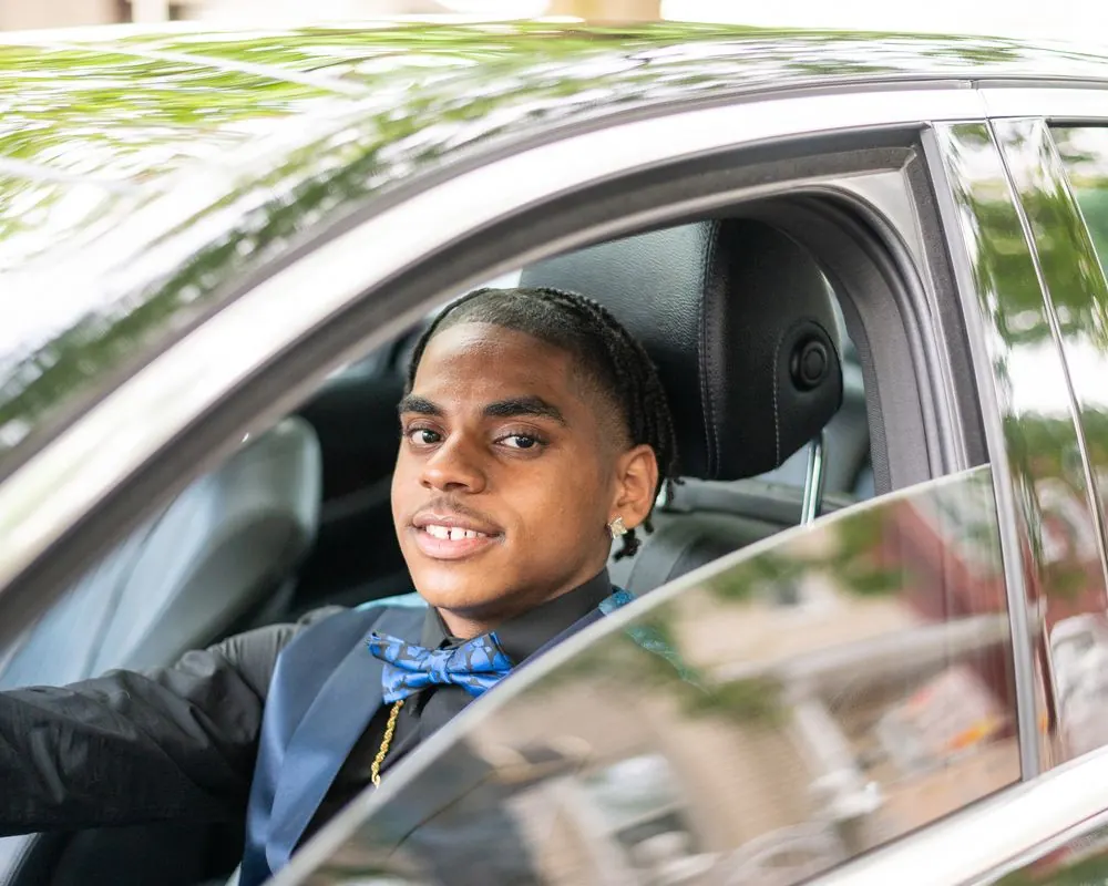 Prom portrait of a young man looking through a car window